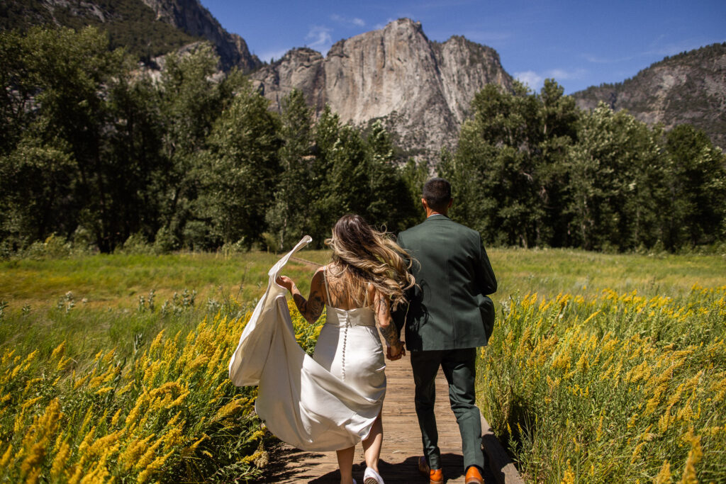 Couple running through a meadow in Yosemite Valley during the best time to elope in Yosemite